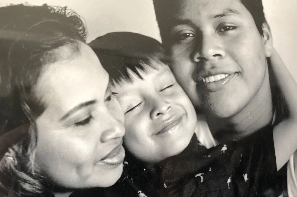 A Guatemalan mother and father smile for a photo with their adolescent son between them.