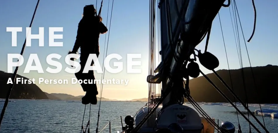 Jessie hangs from the ropes of her sailboat, peering into the sunset over the horizon.