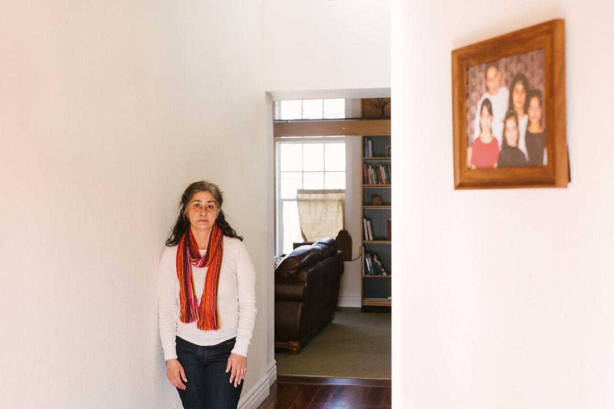 Jessica Gonzales Lenahan stands to the left of a doorway in their home with a family portrait on the right wall