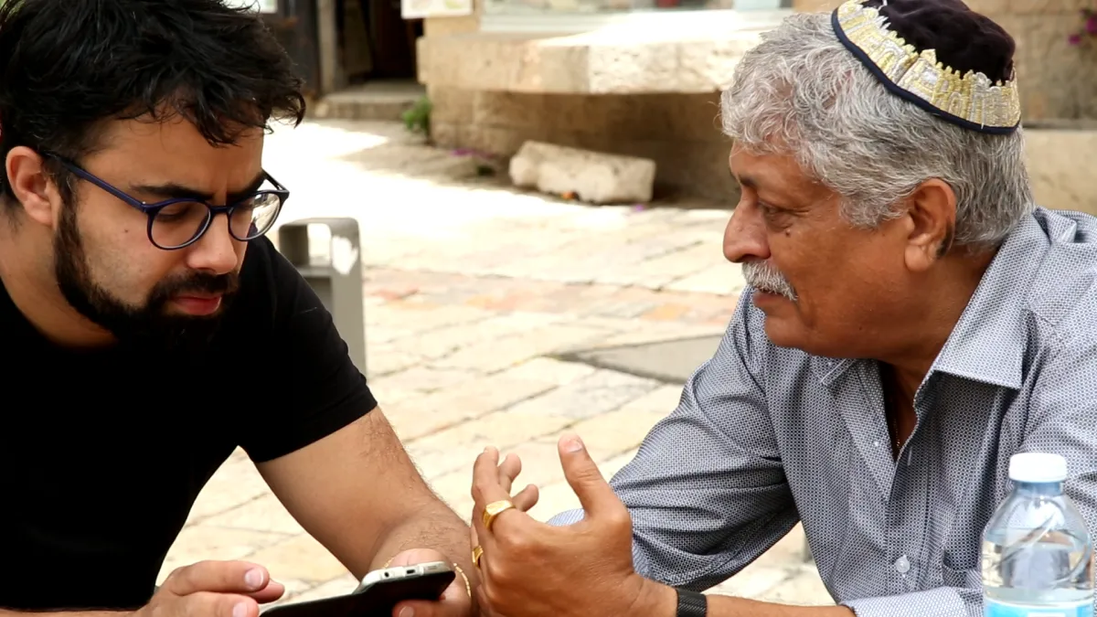 An older man in a yarmulka speaks with younger bearded man.  