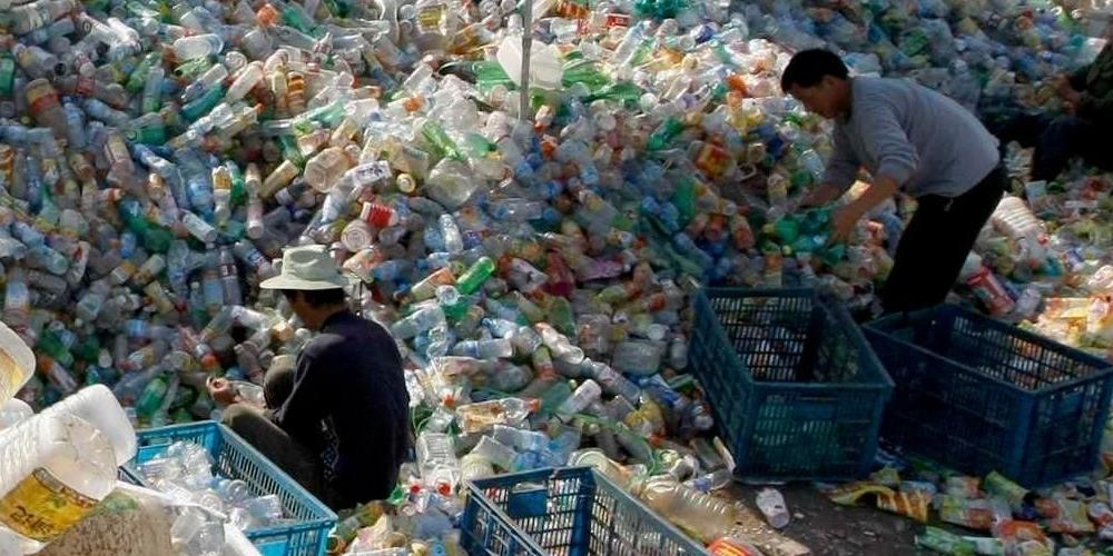 Two people searching through piles of plastic bottle