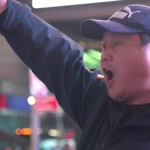 A person in an inner city raises their arms and enthusiastically yells in protest.