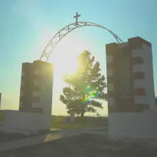 Wounded Knee Memorial arch framing a tree with a ray of sunlight