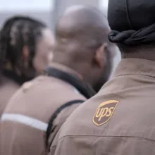 Photo of several UPS workers at an organizing event facing away in their brown uniforms.