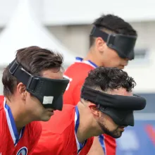 Three Chilean soccer players -  wearing black out masks and red shirts -  prepare for play at the Parapan American Games in 2023.