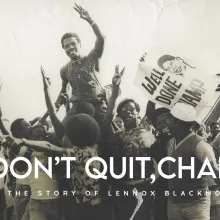 A black and white image of a Black man being carried by a group of people in celebration, with signs reading "well done, champ"