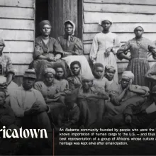 Black and white photograph of a group of enslaved African Americans standing in front of a building