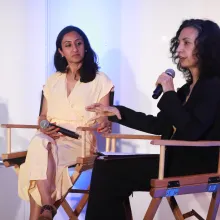 Two women sit on director's chairs.