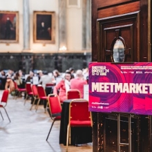 Doors open into a crowded ballroom with round tables, a sign for the Sheffield DocFest “MeetMarket” marks the event on the door.
