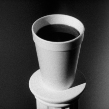 A black and white image of a cup holding a dark liquid.
