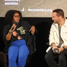 Two filmmakers seated on director's chairs look at each other during a Q&A.