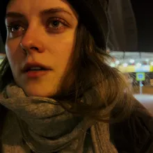 On a street at night, a Russian woman stares behind the camera.