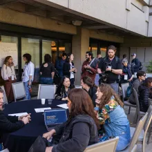 Outside in a courtyard, groups of filmmakers sit around circular tables.