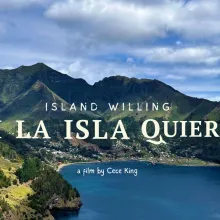 A volcanic archipelago is vividly green and surrounded by blue ocean. Nestled in the middle is a small town. Text overlays the image. The biggest in the middle says "SI LA ISLA QUIERE" with the English translation "Island Willing" above and "Film by Cece King" below.