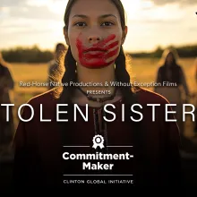 A Native American woman with a red handprint over her mouth. There is a field and four other figures in the background. Stolen Sisters is written in white letters across the image