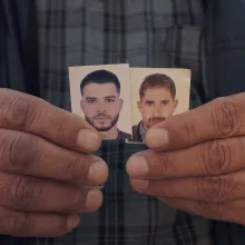 hands hold two small pictures of young men side by side 