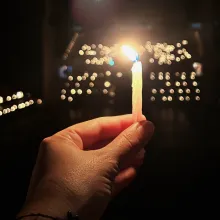 a hand hold a camera in front of far away lights. 