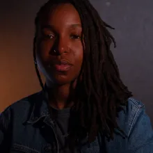 Head shot of black person with moody and multi colored neutral lighting. they glow. 