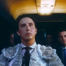 Inside a van, a man in an elaborate bullfighting outfit sits surrounded by his entourage.