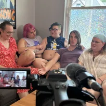 Five individuals sit on a couch in front of a camera