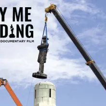 A confederate monument is being lifted by a crane off of its pedestal.