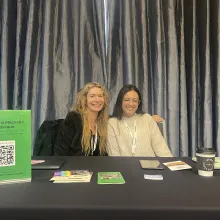 Two white women sit at a booth.
