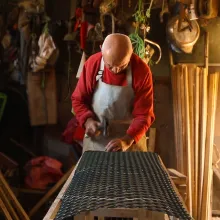 A man in a red shirt beds over a worktable.