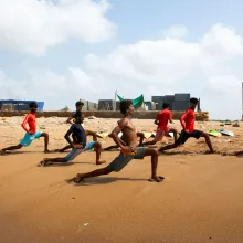 A group of men doing lunges on the beach