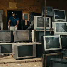 A man stands in a room full of old TV screens.