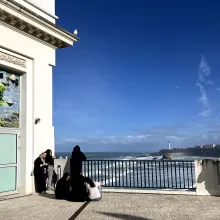 Overlooking crashing waves, a small group of people relax in front of a FIPADOC poster.