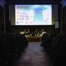 A packed theater with a screen announcing a CPH:DOX panel features four people seated at a stage holding mics mid-conversation