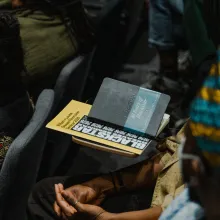 Close up shot of a Blackstar program and notebook on top of a desk, amid a number of Black folks seated as if for a lecture