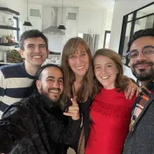 A selfie of three men and two women, all smiling and dressed nicely, taken in a spacious, white kitchen