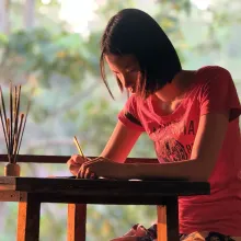 Teenage girl sits at table making art