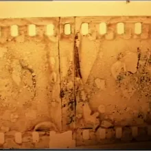 Orange image of a blackened strip of celluloid running parallel to the frame