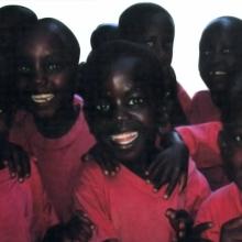 A group of children wearing matching red shirts smile at the camera.