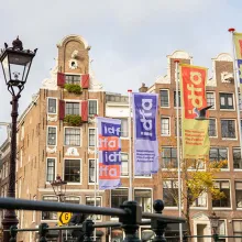 Colorful IDFA 2021 flags fluttering against a brownstone building in Amsterdam. Photo by Roos Trommelen. Courtesy of IDFA.