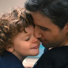 Ady Barkan is a white male American activist seen here sharing an affectionate moment with his child. Image from Nicholas Bruckman’s ‘Not Going Quietly.’ Courtesy of Michael Dwyer/POV. 