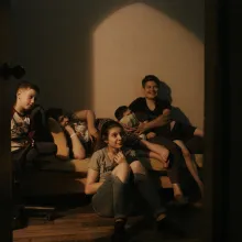 A Ukrainian family of five sits in their living room watching a film that they made about life during wartime. From Iryna Tsilyk’s 'The Earth Is Blue as an Orange'. Courtesy of the filmmaker.