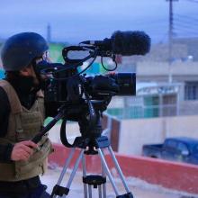 The late Brent Renaud, wearing a protective helmet and bulletproof vest, films on a rooftop. Photo courtesy of of Jeff Newton