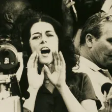Activist Lois Gibbs is a white woman with short dark hair seen shouting to a crowd in an archival image. From Mark Kitchell’s 2012 film 'A Fierce Green Fire'. Courtesy of Mark Kitchell