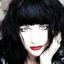 Lydia Lunch, a white woman with black hair cut in bangs. She is wearing bright blue contact lenses and red lipstick. From Beth B’s ‘Lydia Lunch: The War is Never Over’. Courtesy of Kino Lorber.