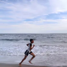  A young Black girl in shorts and a t-shirt runs along the seashore. Tai Sheppard in ‘Sisters on Track’ (directors: Corinne van der Borch, Tone Grøttjord-Glenne). Courtesy of Netflix