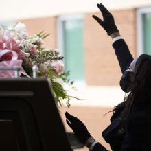A masked Black woman funeral worker at a funeral at Franklin Avenue Baptist Church, New Orleans. She is standing next to a casket. From the 'Frontline' documentary ‘Death Is Our Business,’ directed by Jacqueline Olive. Courtesy of PBS Frontline.