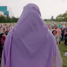 A woman wearing a hijab stands on a podium looking out at a crowd. Photo: Capital-K Pictures. Courtesy of POV.