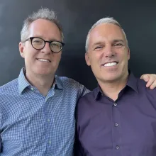 Outgoing DOC NYC Artistic Director Thom Powers (left) is a white man with grey hair and glasses and a blue botton-down shirt. DOC NYC’s new artistic director, Jaie Laplante (right) is a white man with white hair and a purple botton-down shirt. Photo courtesy of Thom Powers.