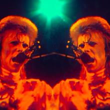 A red overlay on a mirrored image of David Bowie singing into a mic, from ‘Moonage Daydream.’ Photo courtesy of NEON.  