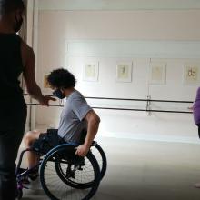 Reveca Torres is a Mexican-American female filmmaker, seen here filming in a large room. She is filming three participants, one of whom is a wheelchair user. Image courtesy of Reveca Torres.