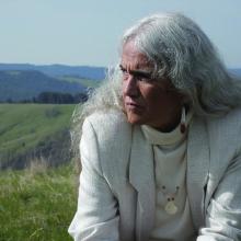 An elder Yurok woman in front of green landscape
