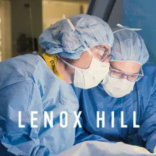 Two doctors in blue scrubs and glasses in an operation.